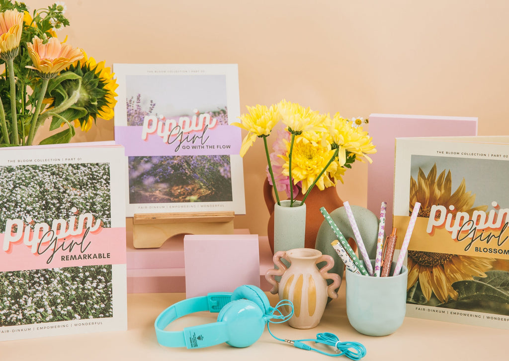 Pippin Girl Bloom book collection styled with flowers, headphones and stationery