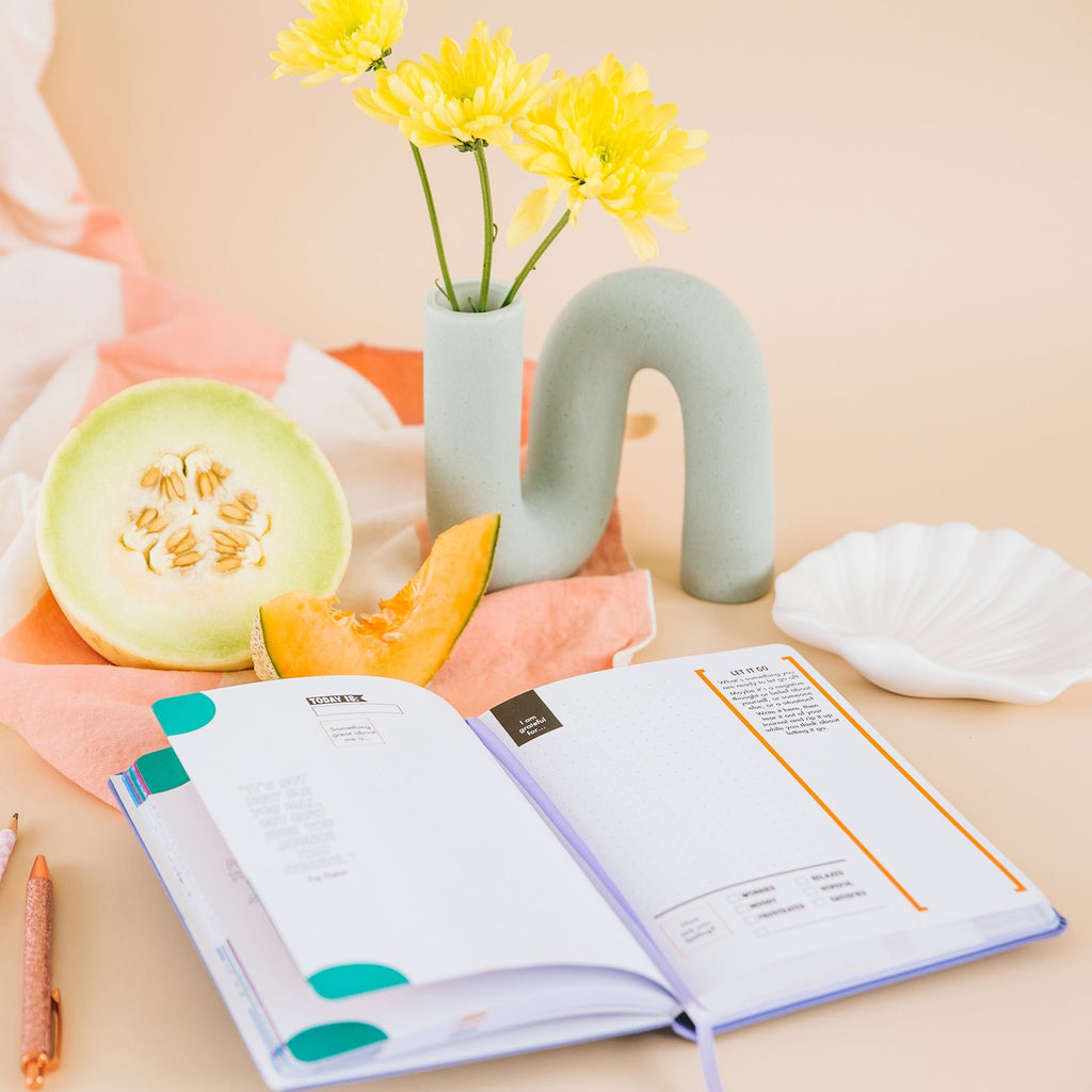 The Grow Journal for teen girls styled with fruit and flowers in a mint vase
