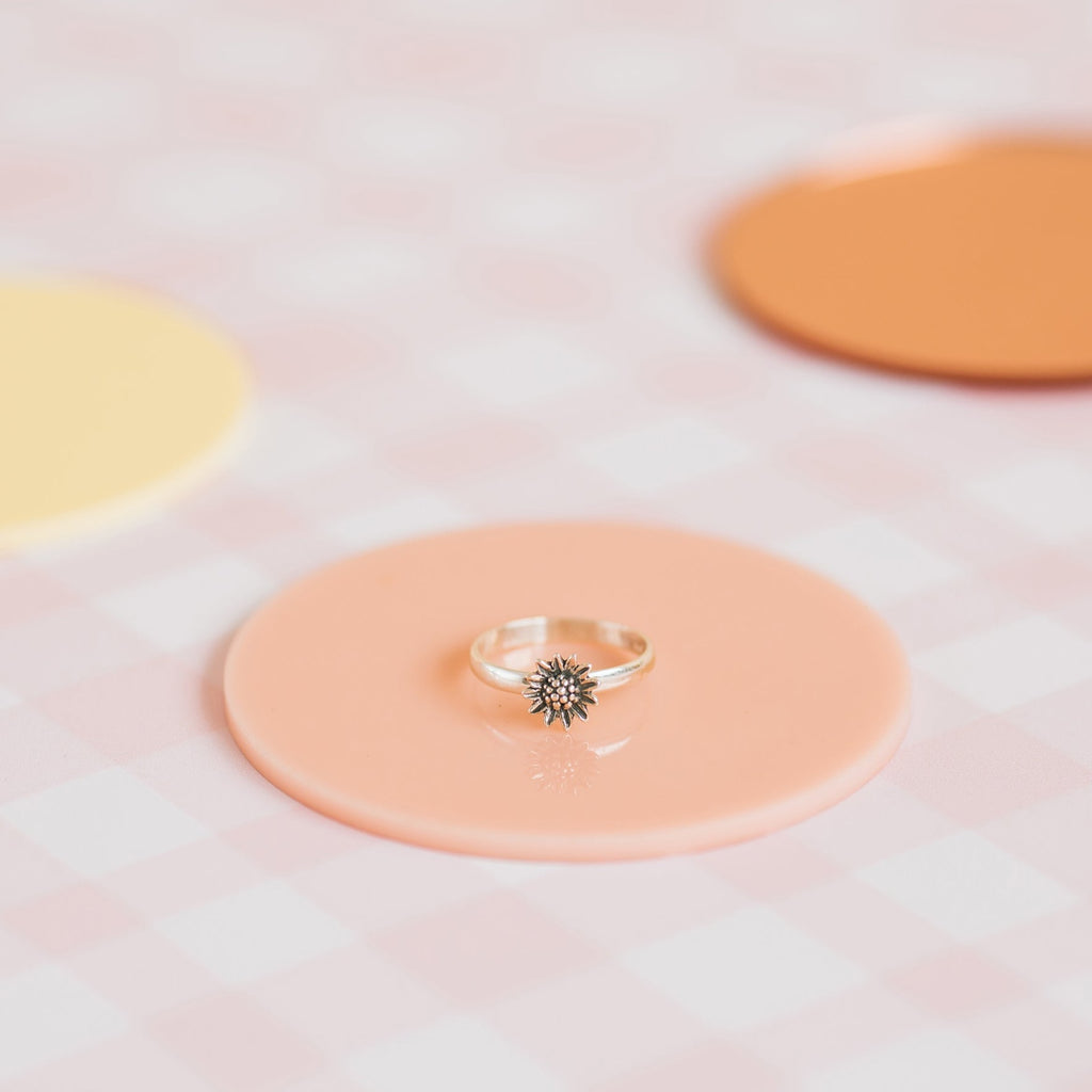 Pippin Girl Bloom Ring styled on peach disc and pink check background