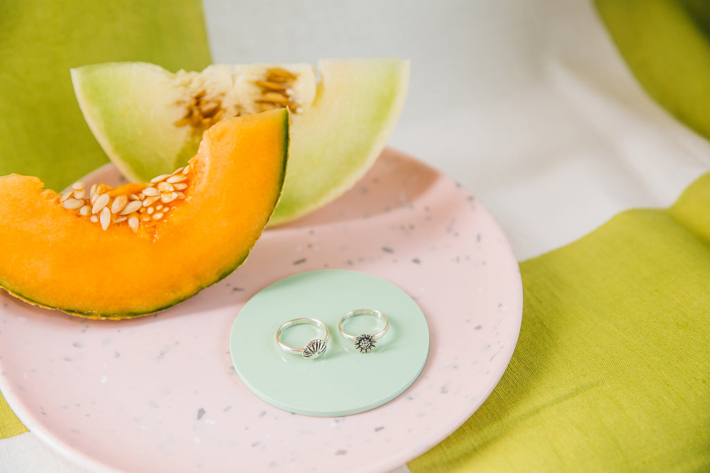 The Treasure Ring and The Bloom ring on a pink plate with slices of melon.
