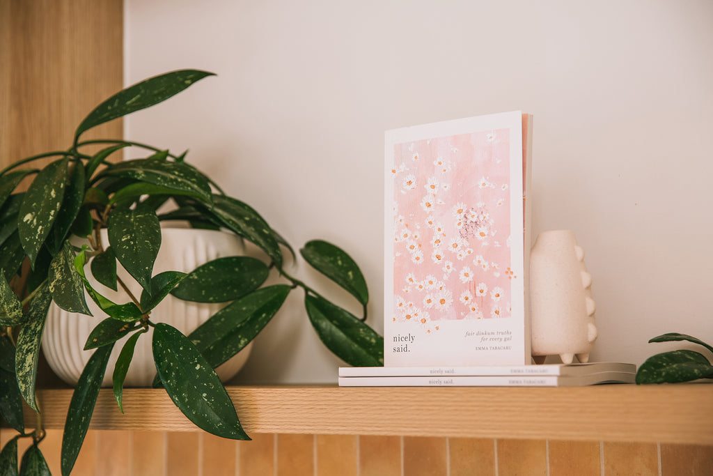 three copies of Nicely Said poetry book for girls on a shelf wiht a healthy hoya plant and ceramic vase