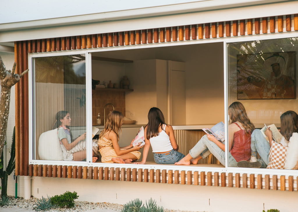 Looking through a large window at teen girls sitting on a bench together reading Pippin Girl resources
