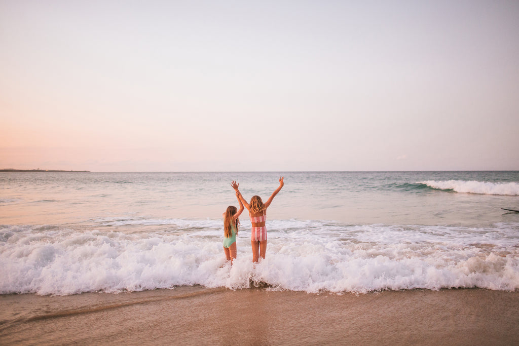 Two girls standing in the breaking surf waves.