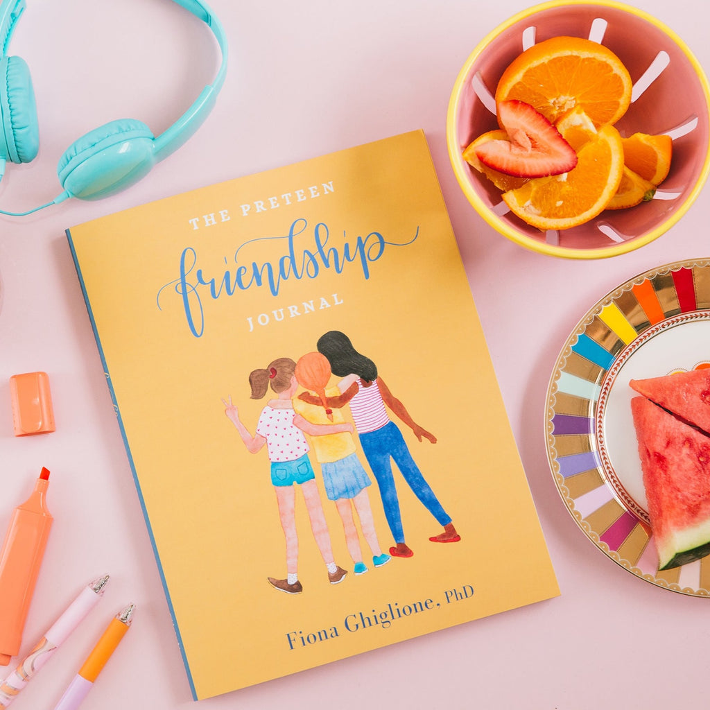 The preteen friendship journal for girls styled with fruit and colourful stationery on a pink background