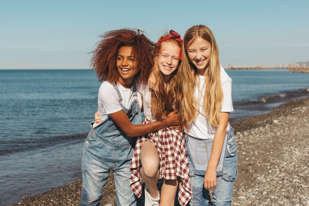 Three friends (girls) at the beach. The ground is rocky.